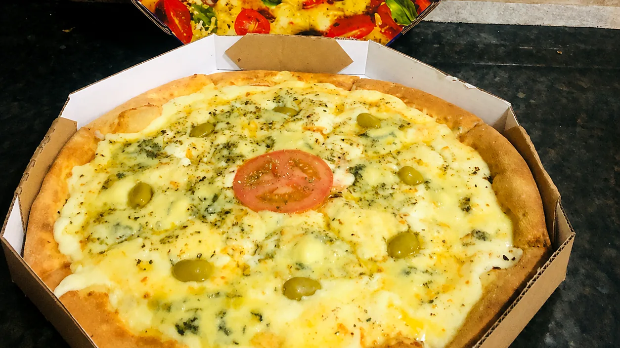Pizza recém-preparada dentro da caixa da Pizzaria Recanto Novo